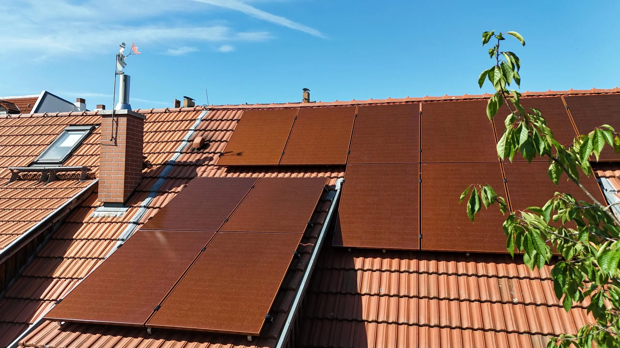 Ein Hausdach mit orange farbigen PV Modulen.