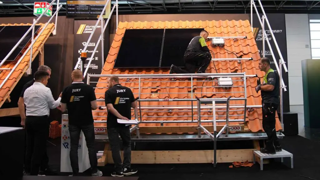 Drei Jury Mitglieder bewerten die Montage einer PV Anlage auf einer Messe.