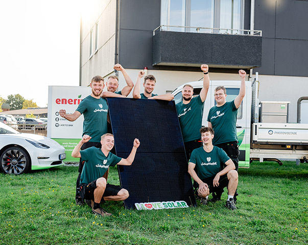 enerix Flensburg - Foto vom Photovoltaik Montageteam das vor einem großen Solarmodul steht.