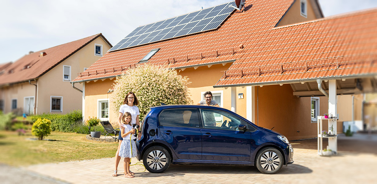 a family and a e-car posing in front of a house with a pv-system