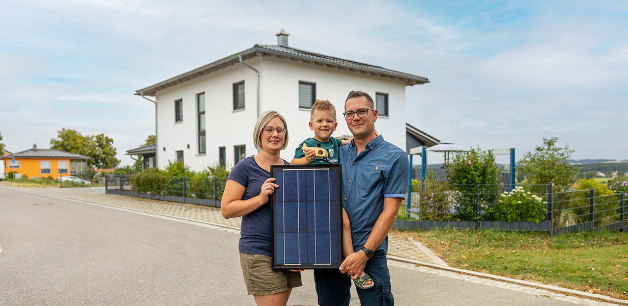 a family posing in front of a house with a pv-system