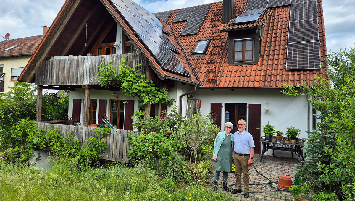 Photovoltaikanlage auf Hausdach. Im Vordergrund Familie Struntz im Garten.