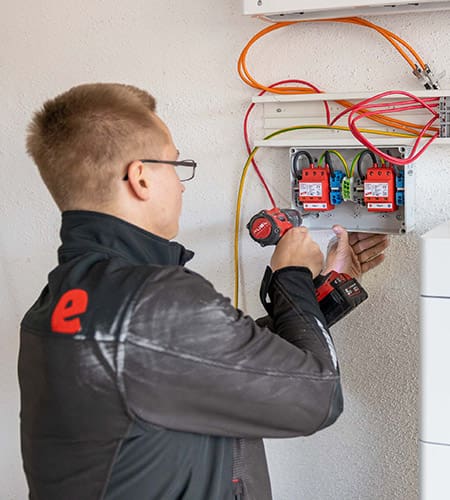 Elektriker installiert Stromspeicher an einer Hauswand