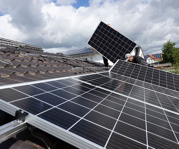 Handwerker befestigen Photovoltaikanlage auf Mehrfamilienhaus