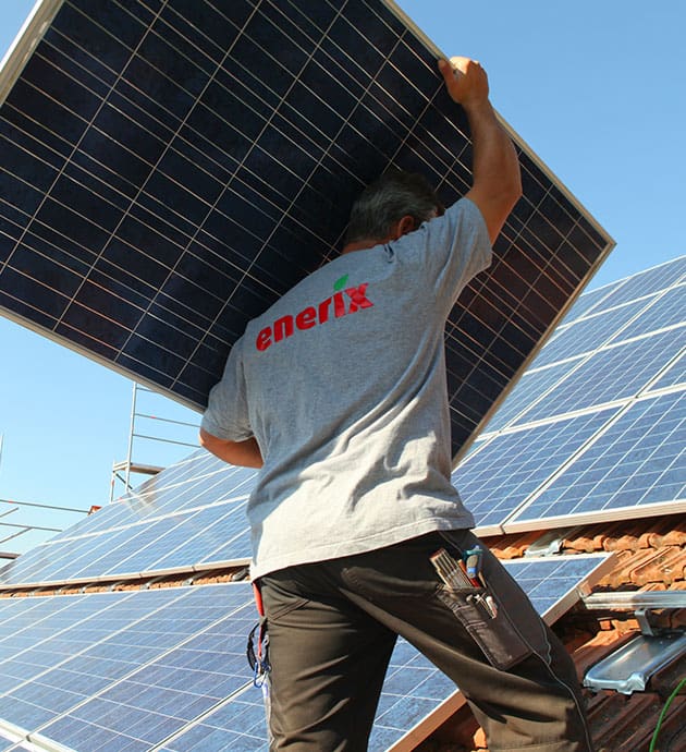 ein Solarteur trägt ein Photovoltaikmodul auf dem Rücken