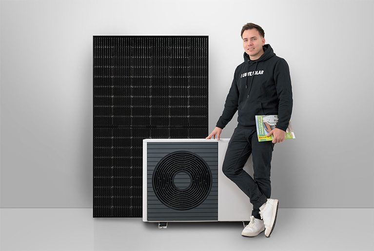 Ein enerix Photovoltaik Experte steht vor einer Wärmepumpe und einem Photovoltaikmodul