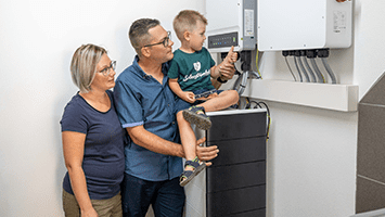 Familie steht vor einem Stromspeicher