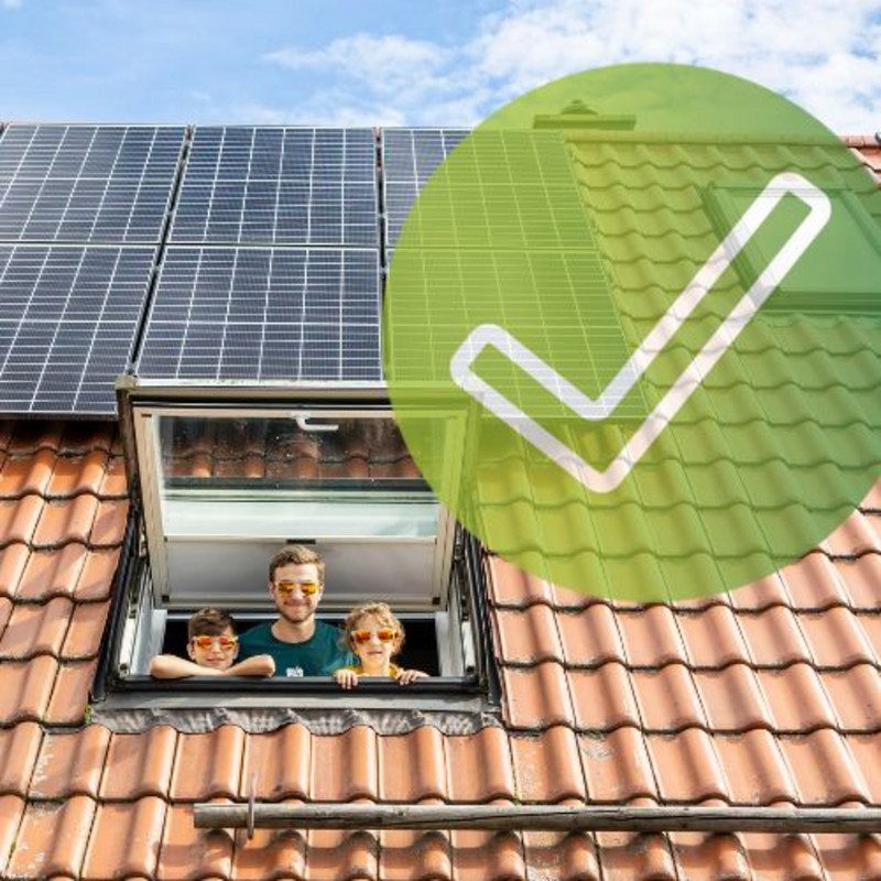 Eine Familie guckt aus einem Fenster eines Hauses mit PV Anlage die für eine Direktvermarktung geeignet ist.